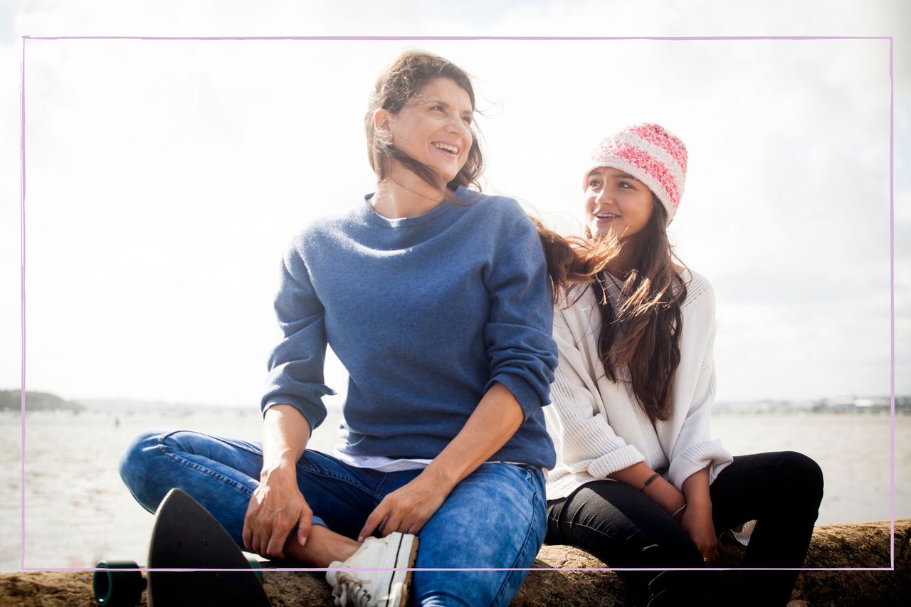 Mother sat with teenage daughter on a beach