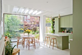 white and green kitchen extension with view through glass doors to garden