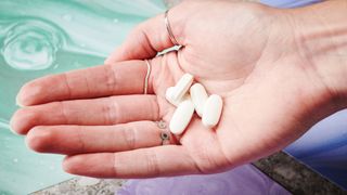 white supplement capsules in the palm of a hand