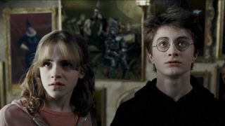 From left to right Hermione and Harry looking concerned in the third Harry Potter movie. There's a knight standing behind them in the portrait.
