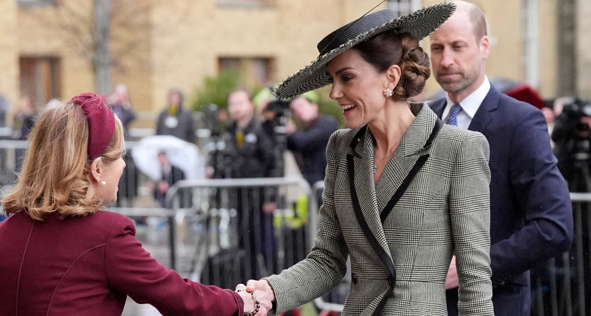 Princess Kate wearing a gray coat shaking hands with a woman
