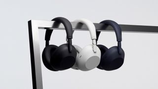 Sony WH-1000XM6 headphones in black, white and blue hung over a bar.
