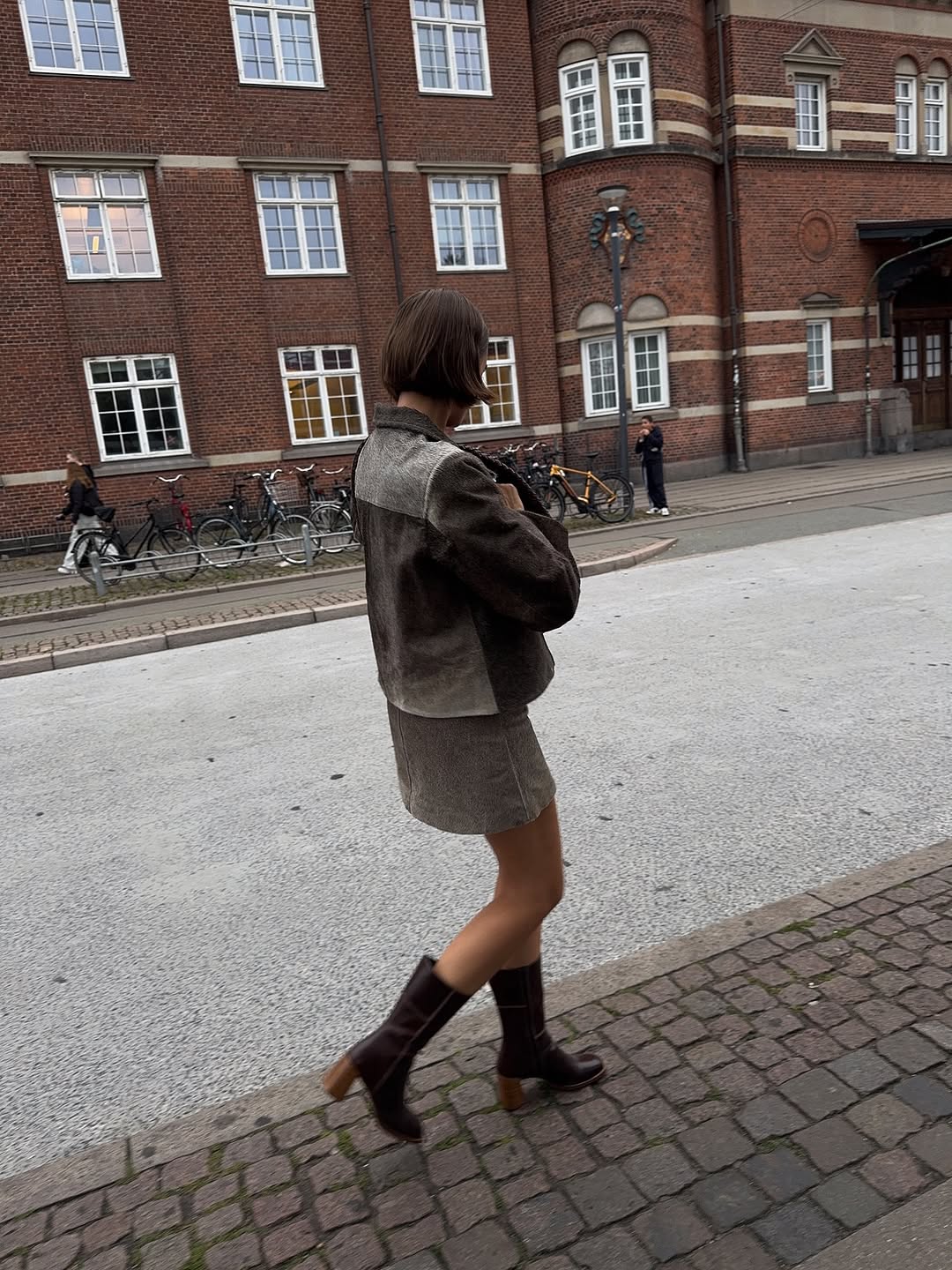 Woman wearing fall boots with skirt outfit 2025.