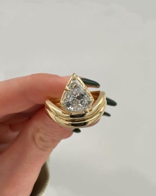 Woman holding up gold Orianne engagement ring.