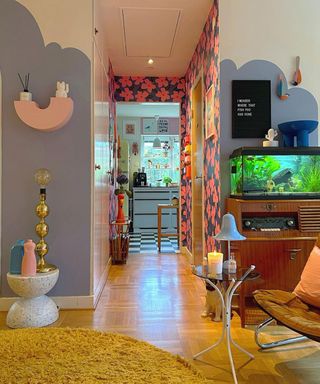 A colorful living area with a desk that looks onto a kitchen