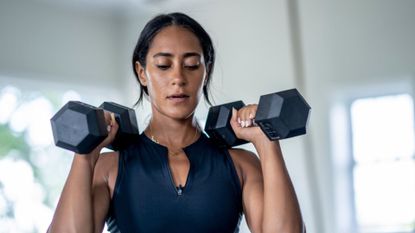 A woman completing a home workout with dumbbells