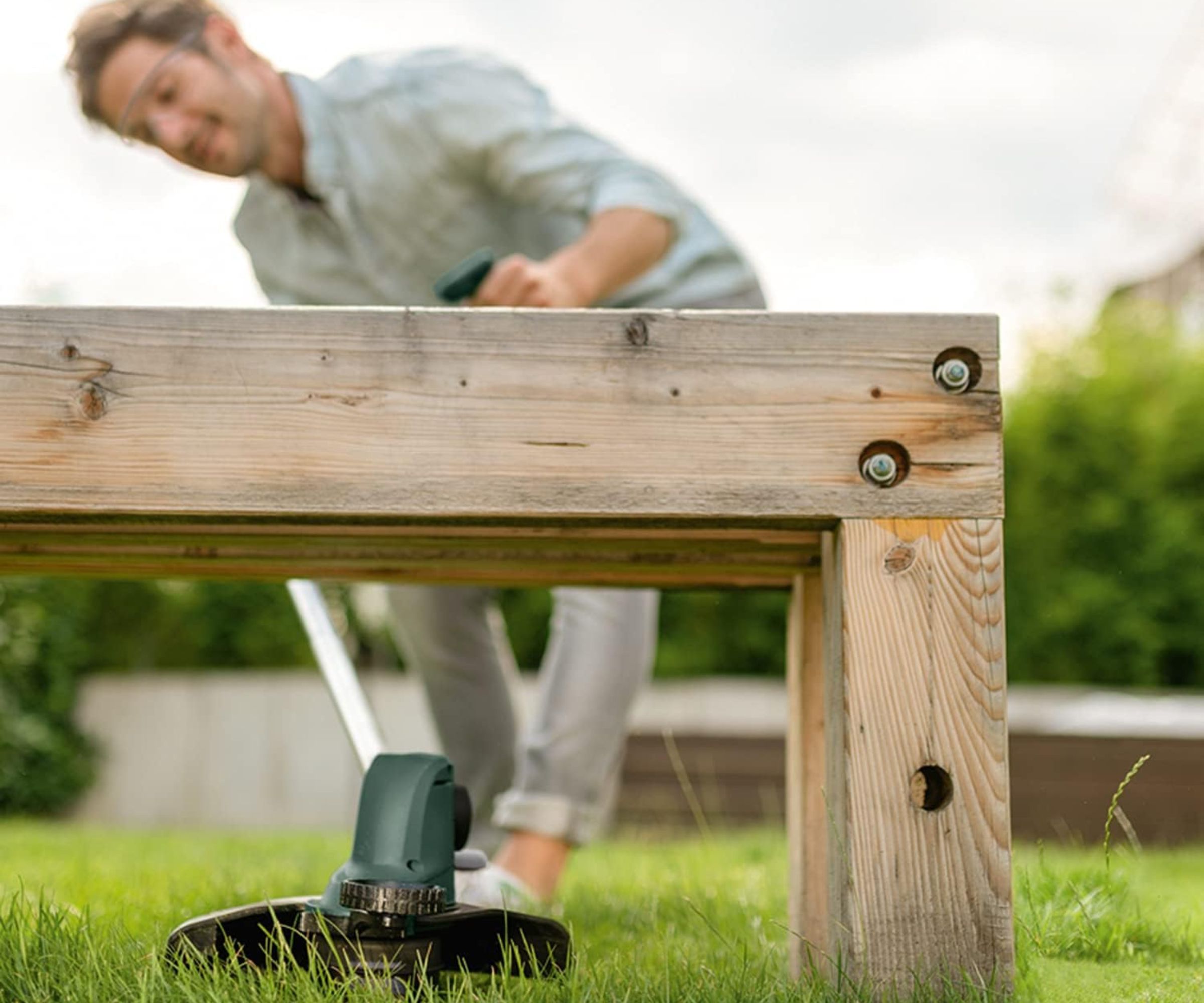 Bosch Grass Trimmer UniversalGrassCut 18 being used under bench