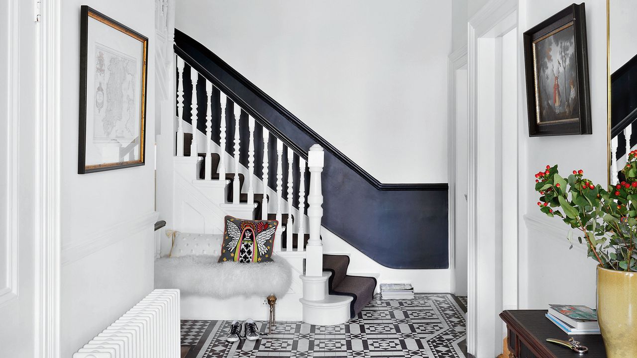 Hallway with black and white patterned floor and white staircase with half the wall painted blue