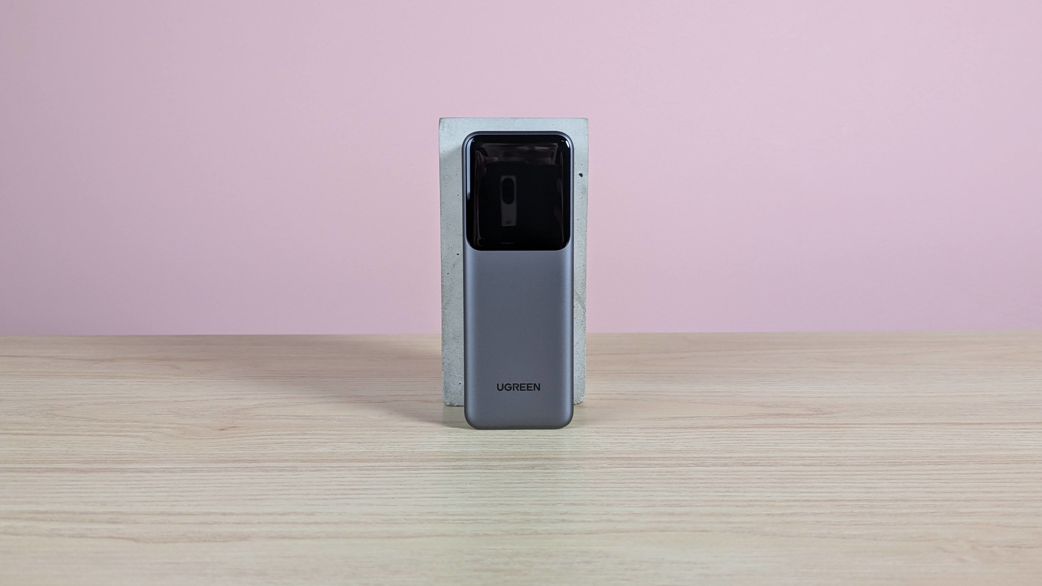UGREEN Nexode Power Bank 20000mAh 165W leaning on plinth on desk with pink background