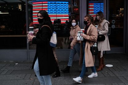 People wearing masks walk through Times Square.