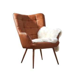 A brown leather chair with a white faux fur throw on it