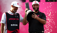 Jon Rahm holds the LIV Golf trophy next to his caddie