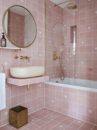 pink bathroom with allover pink square tiles, gold fixtures and fittings, floating basin