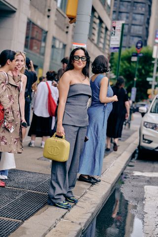 woman at new york fashion week wearing a gray strapless top and gray trousers and sneakers