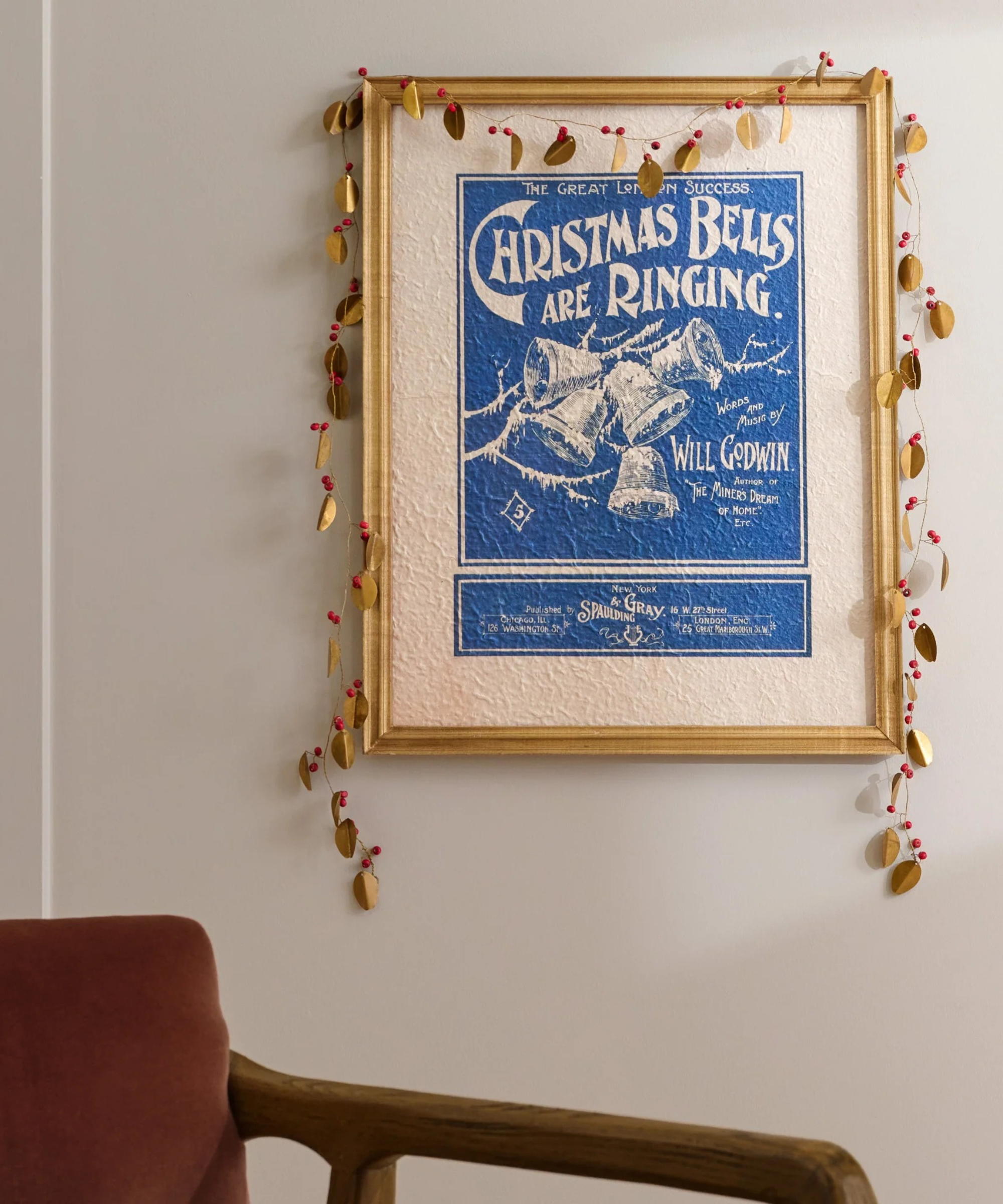 a Christmas poster with brass garland hanging around the frame