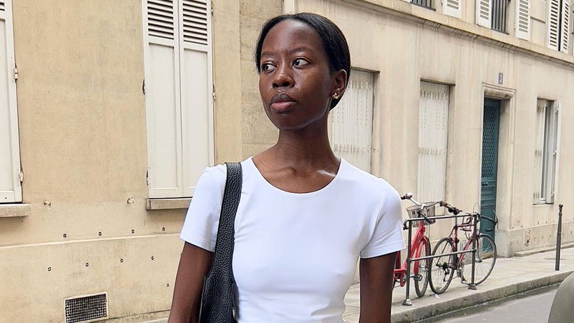 A woman wearing a white t-shirt, grey pencil skirt, and black bag