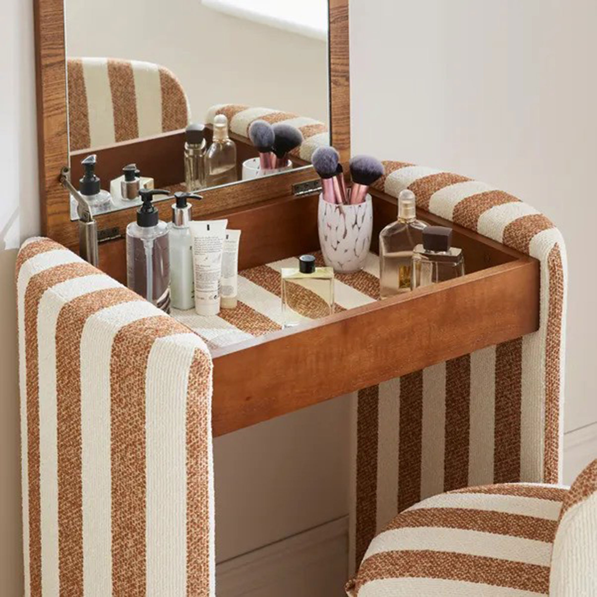 Dressing table in striped fabric in a white bedroom with the lid open and the chair pulled out