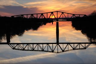 A truss bridge over a river at sunset in Northport.