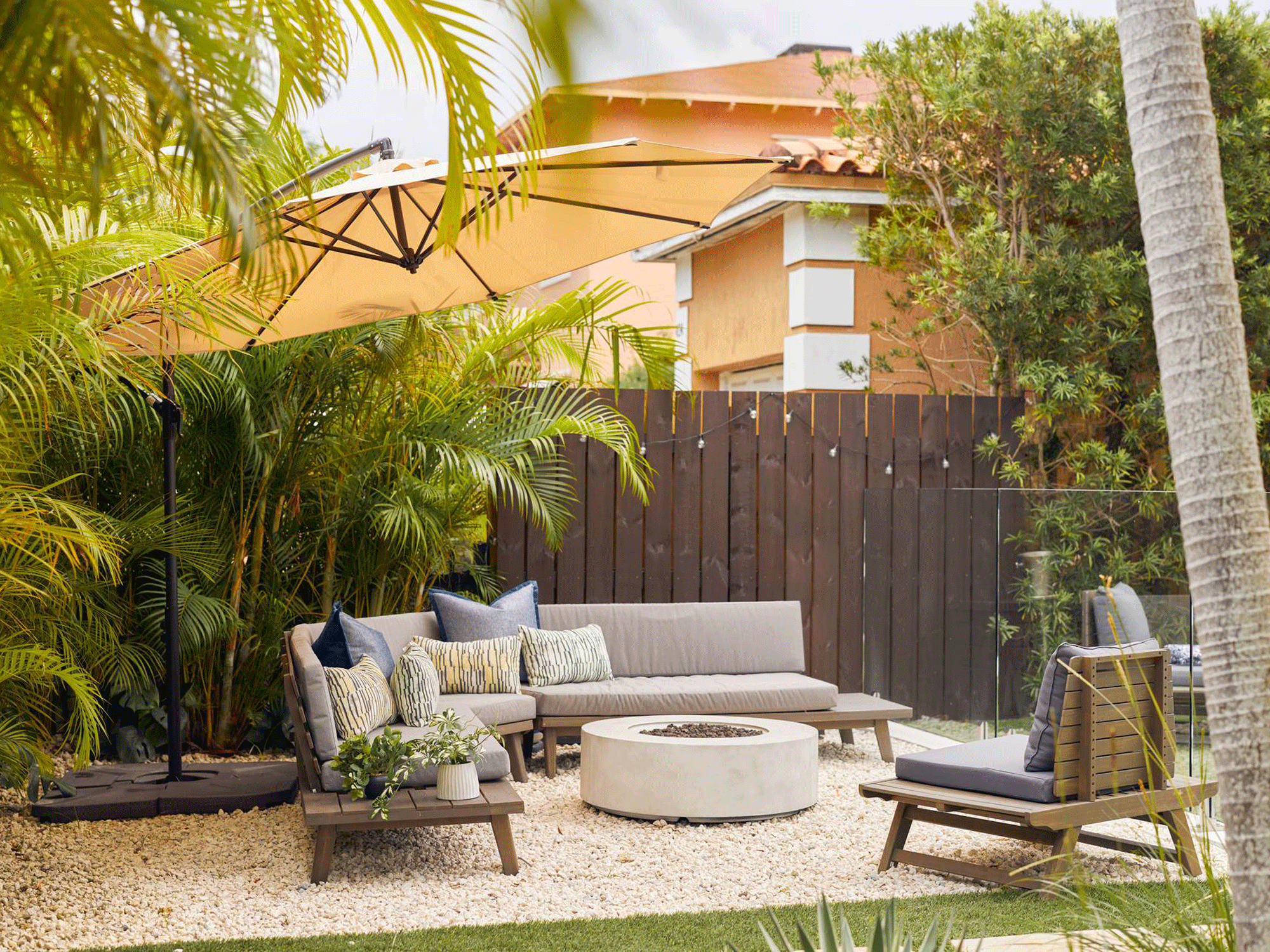 backyard with sofa, chairs, table, parasol and fire pit