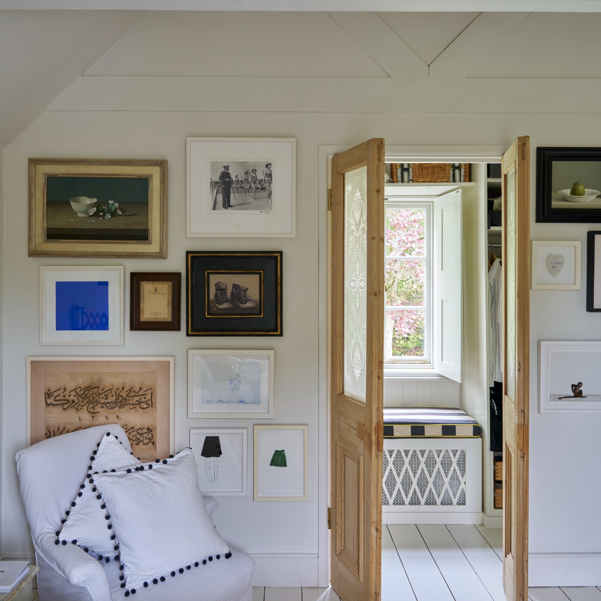 A bedroom painted in Farrow &amp; Ball's Wimborne White shade with one wall dedicated to a gallery wall