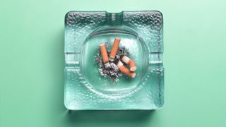 Crushed cigarettes in glass ashtray