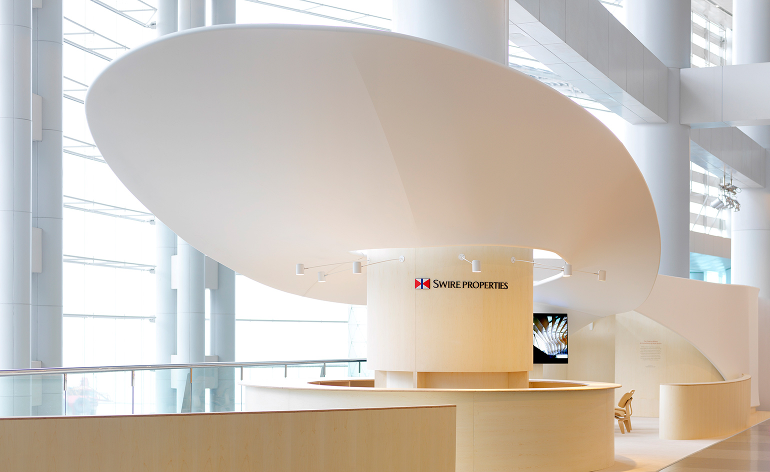 Interior room, floating ribbon in a figure eight shape winding around the front column where the circular bar area is situated, windows, white wall framed structure of the building