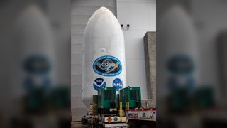 a large white cylinder with a nasa logo and an emblem reading "GOES U" sits on a flatbed truck