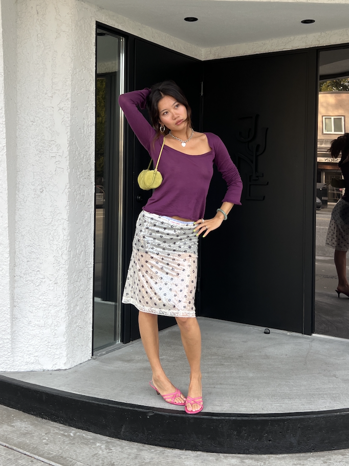 Vivian Li wearing a purple shirt and green bag and white skirt