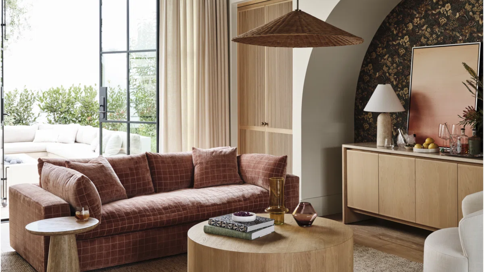 a cozy living room with a grid-printed couch, a round coffee table, and a rattan pendant