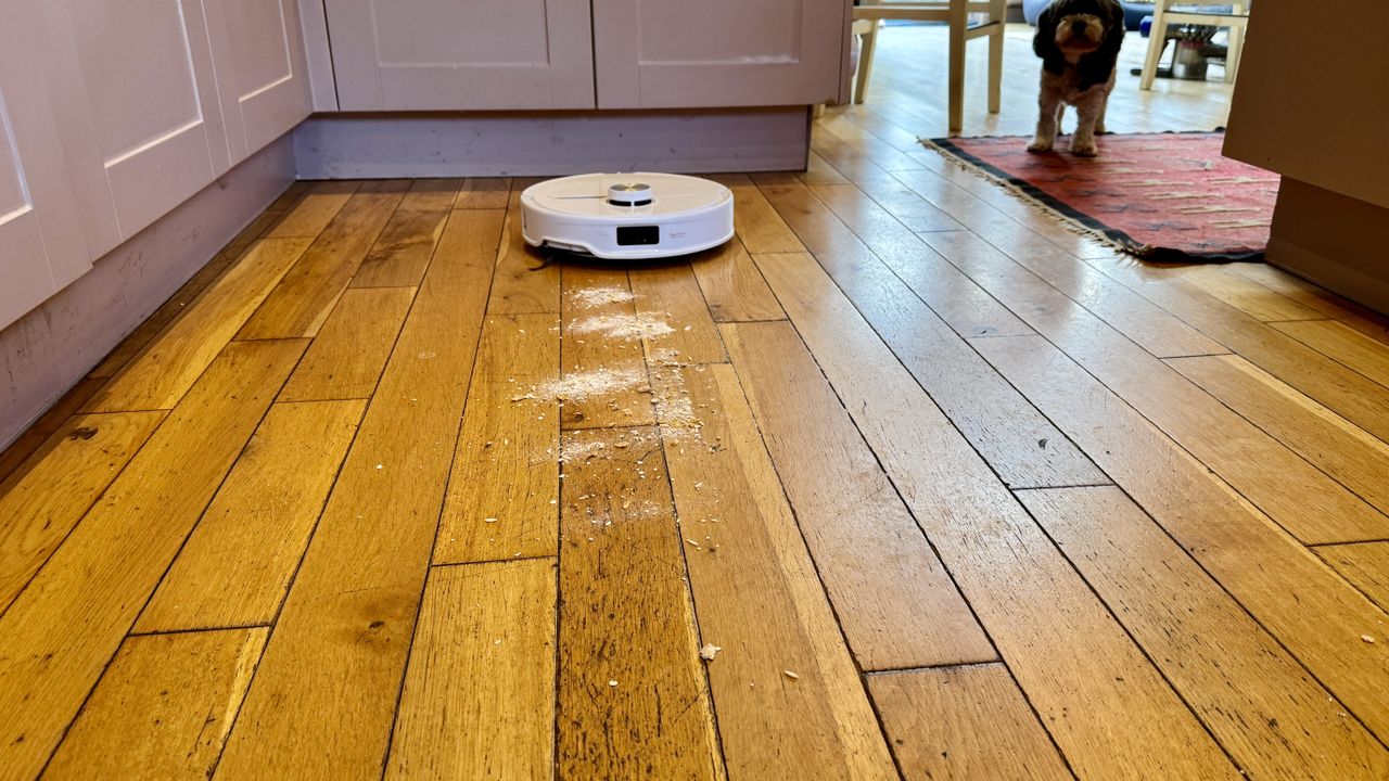 Roborock Qrevo Master robot vacuum with debris sprinkled in front of it on a hard floor, for the suction test