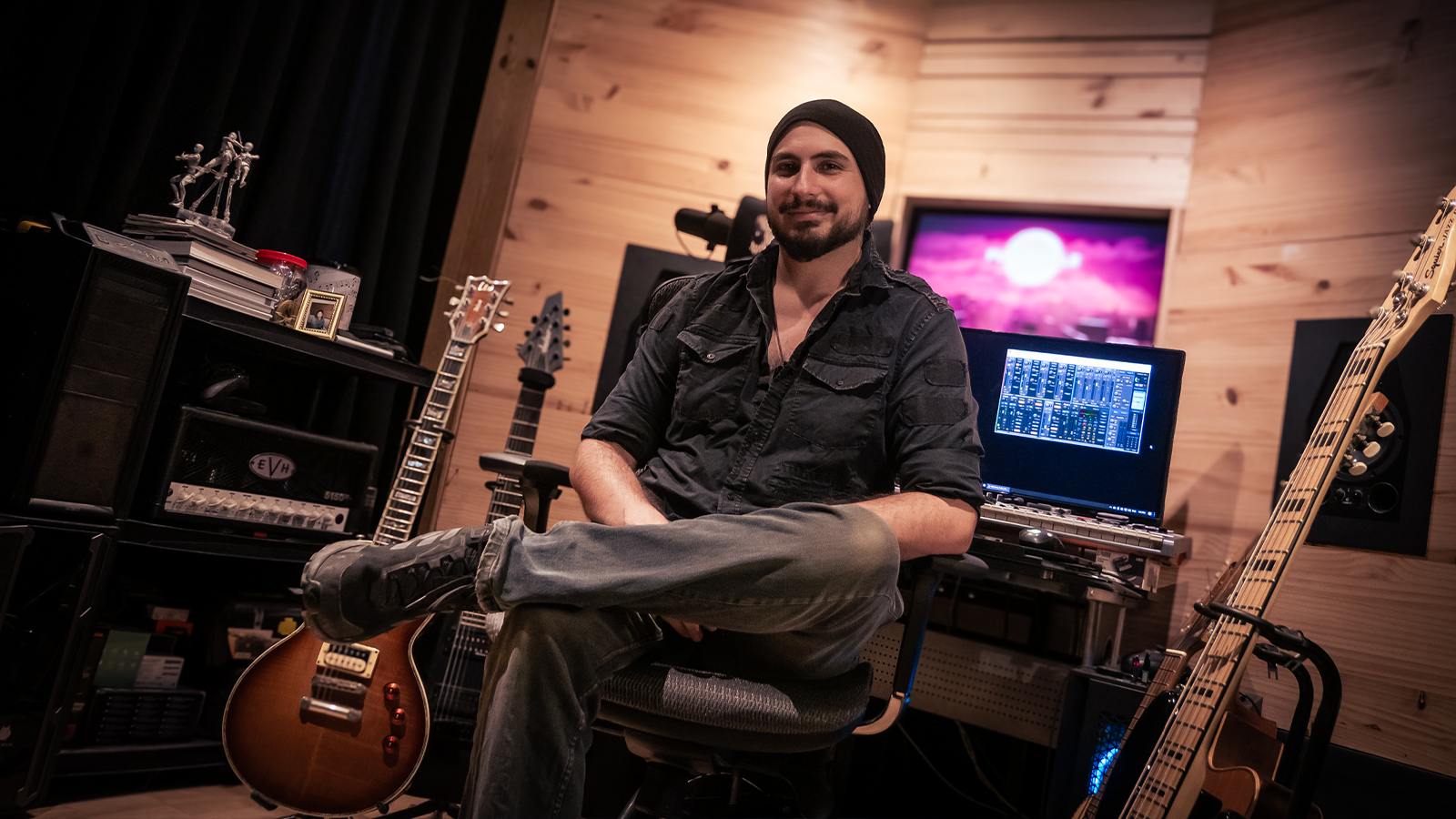 A man in a game studio surrounded by guitars