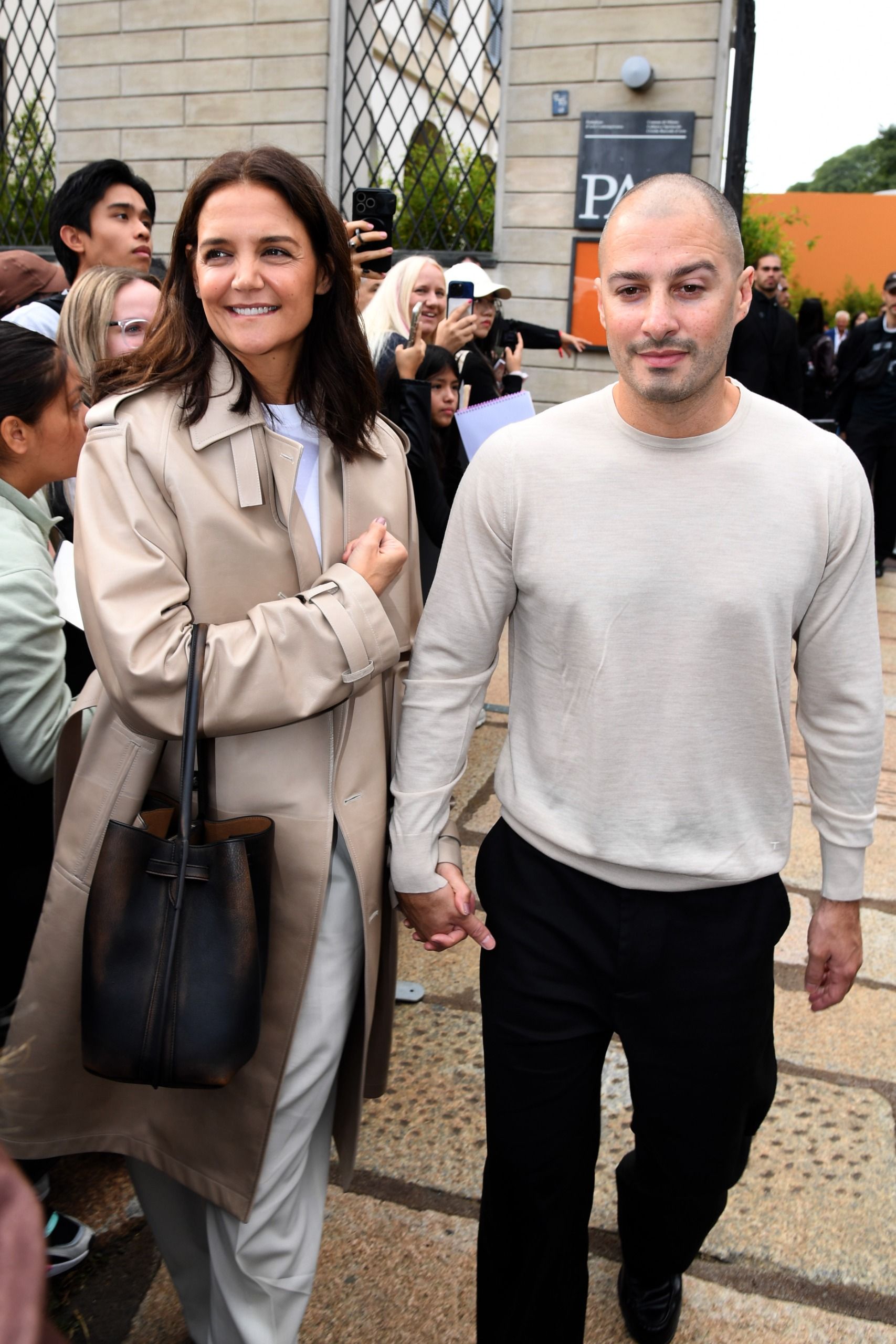 Katie Holmes at Milan Fashion Week wearing a trench coat and classic loafers