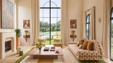 Living room with floor-to-ceiling window, sofa with geometric upholstery, large wood rectangular coffee table, beige and green rug and green armchairs