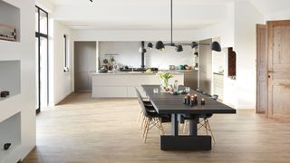 A white kitchen with a wooden floor and a black dining table
