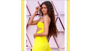 Zendaya with long wavy hair and wearing a yellow dress as she attends the 93rd Annual Academy Awards at Union Station on April 25, 2021 in Los Angeles, California