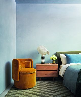 bedroom with blue walls, green bed, rust chair, patterned carpet and mid century chest