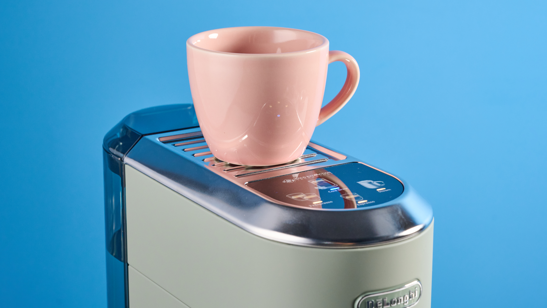 DeLonghi Dedica Duo in the green colorway with accessories photographed on a blue background.