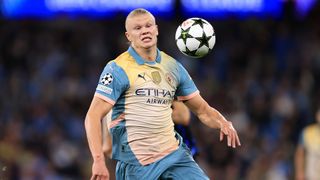 Erling Haaland chases down a bouncing ball wearing a yellow and blue Manchester City shirt.