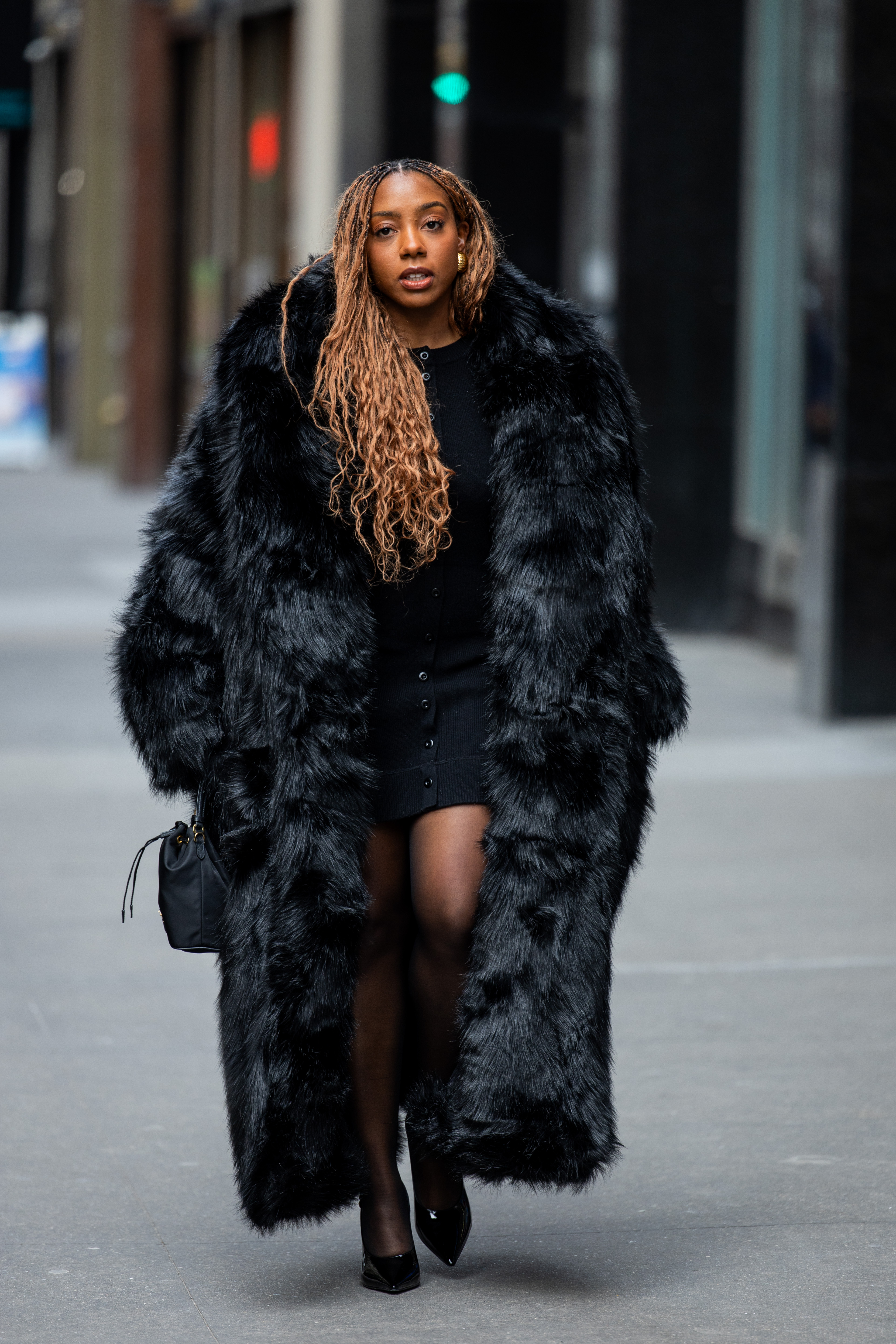 a woman wearing a black fur coat over a knit mini dress and heels in street style