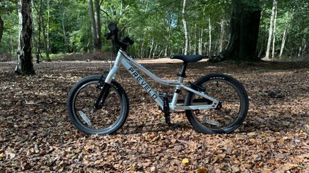 A Prevelo Alpha Two kids bike viewed side on in a clearing in the woods