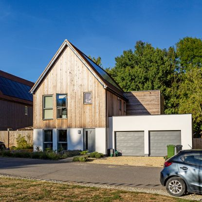 Front of house with white and wooden cladding and double garage