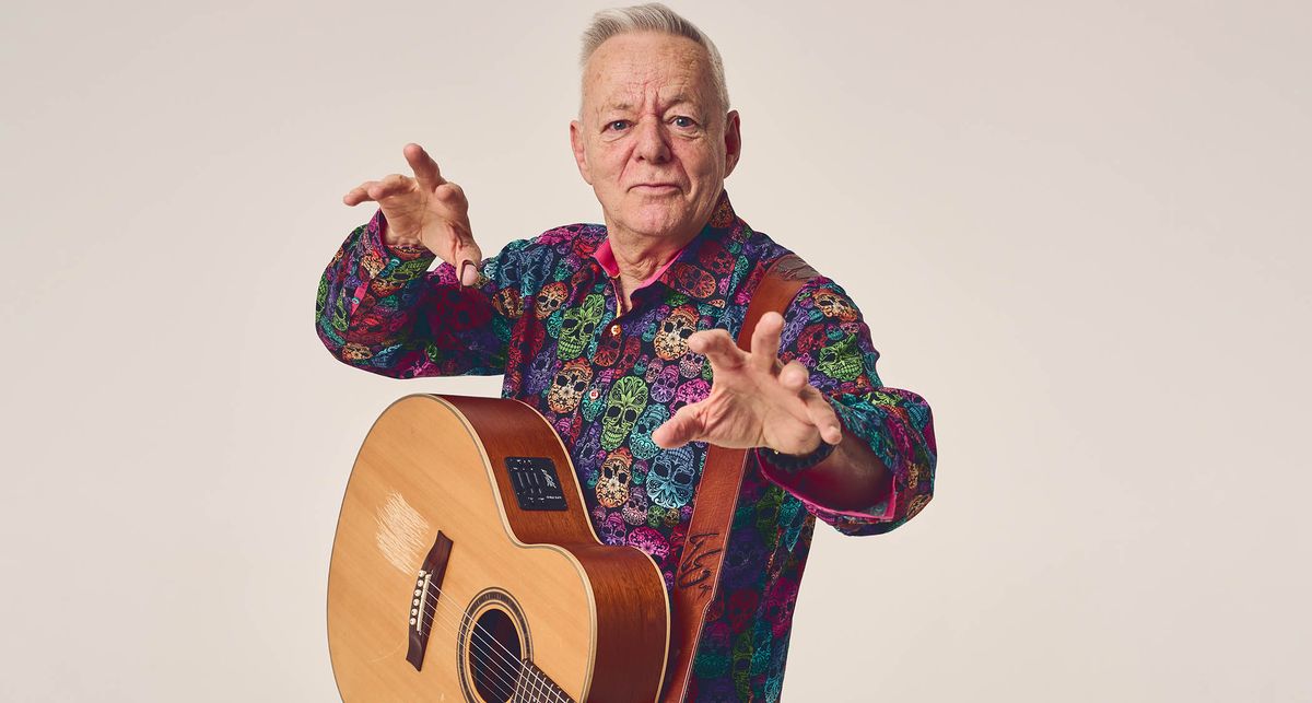 Tommy Emmanuel wears a loud shirt and poses with his Maton acoustic