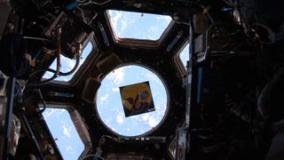 The children's book "The Wizard Who Saved the World" by Jeffrey Bennett floats inside the International Space Station's Cupola observation deck with the Earth serving as a stunning backdrop. The book is one of five on the station for the Story Time From Space educational project.