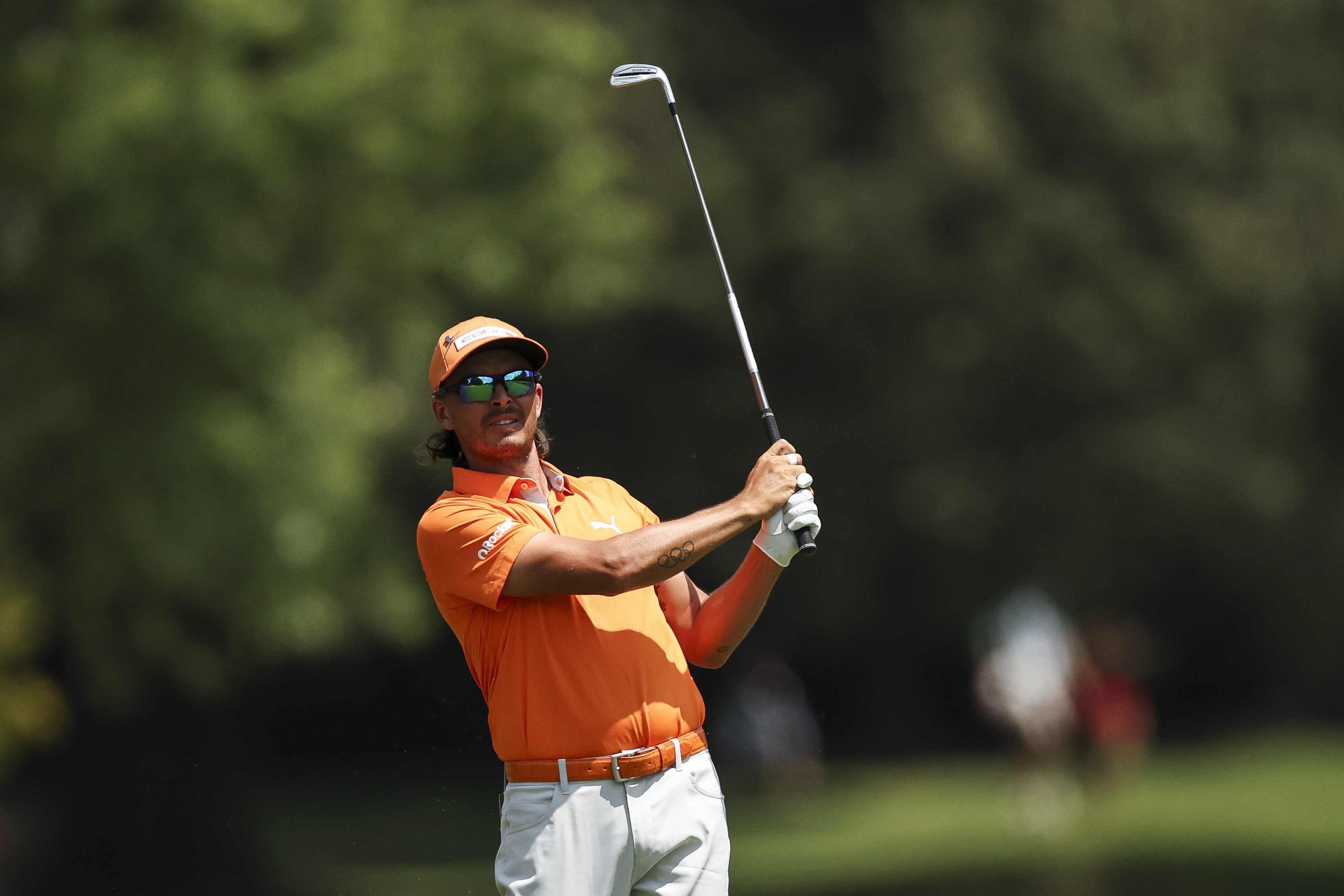Rickie Fowler wearing orange plays an iron shot