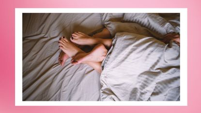 the feet of a couple tangled up in bed on a pink background