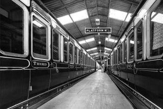 Carriages flanking a central platform in the Didcot Railway Centre, lit from above. Without much colour, we made a mono conversion for a study of lines and shapes