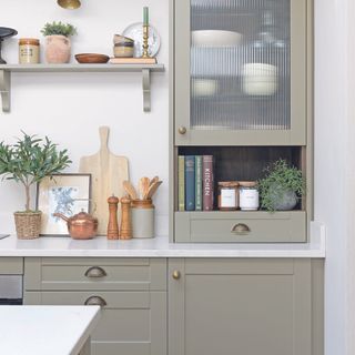 Sage green kitchen with gold handles and fluted wall cabinet