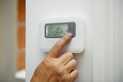 Person adjusting digital thermostat