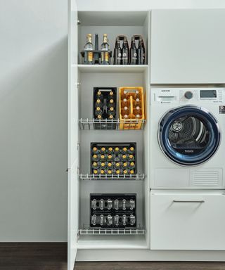 wire pull out shelves with bottle on in white utility room cupboard