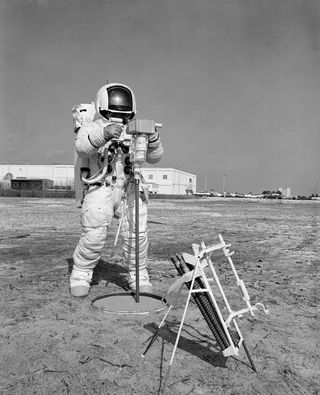 During an extravehicular activity walkthrough on Jan. 28, 1970, astronaut Fred Haise, Apollo 13 lunar module pilot, uses an Apollo Lunar Surface Drill to make a 10-foot (3 meters) hole for a heat flow probe. On the lunar surface, an electronic instrument will measure the outward flux of heat from the hole.